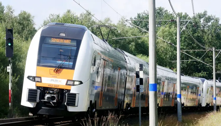 Der Rhein-Express fährt auf einer Sonderfahrt durch eine grüne Landschaft.