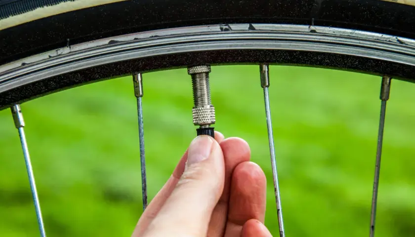Hand schraubt am Fahrradventil. Ein kleines Teil am Ventil wird gerade befestigt, um das Fahrradventil wechseln zu können.