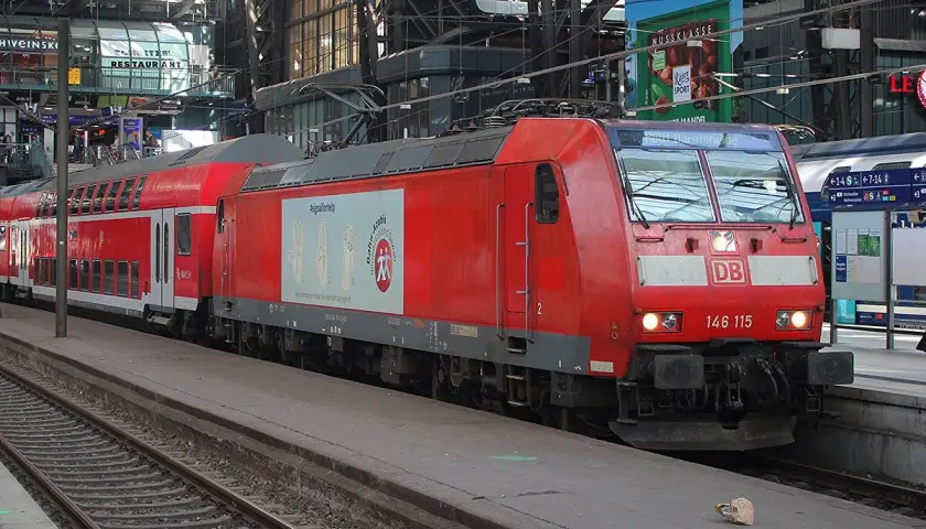 Rote Lokomotive der Baureihe 146 mit Doppelstockwagen im Bahnhof.