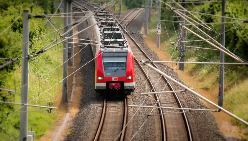 Rote DB-Bahn fährt auf Gleisen. Hier kann man alte Fahrscheine umtauschen, wenn man die Reise neu plant.