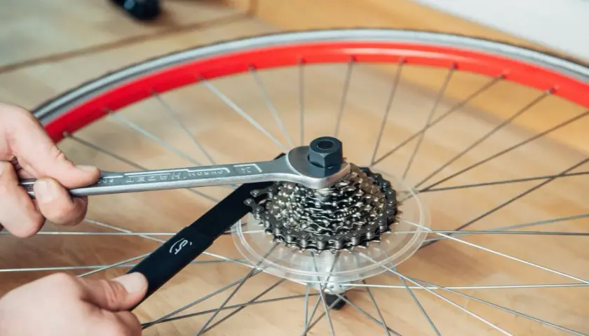 Werkzeug löst die Kassette am Fahrrad. Hände halten Werkzeug und Kettenpeitsche, um die Kassette zu wechseln.