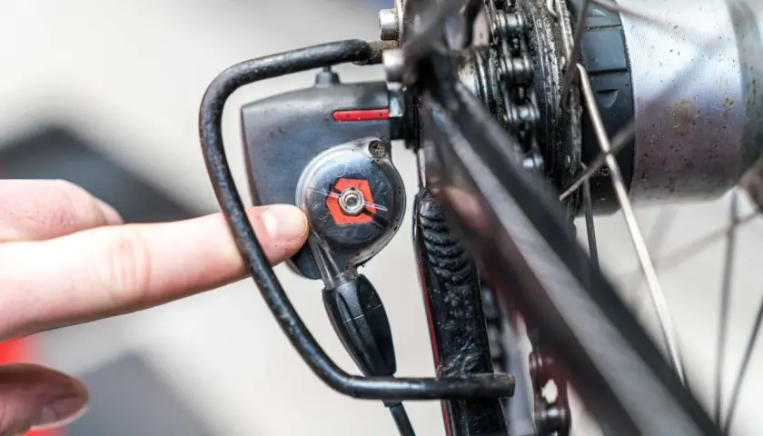 Finger dreht an Einstellschraube, um die Nabenschaltung am Fahrrad zu justieren.