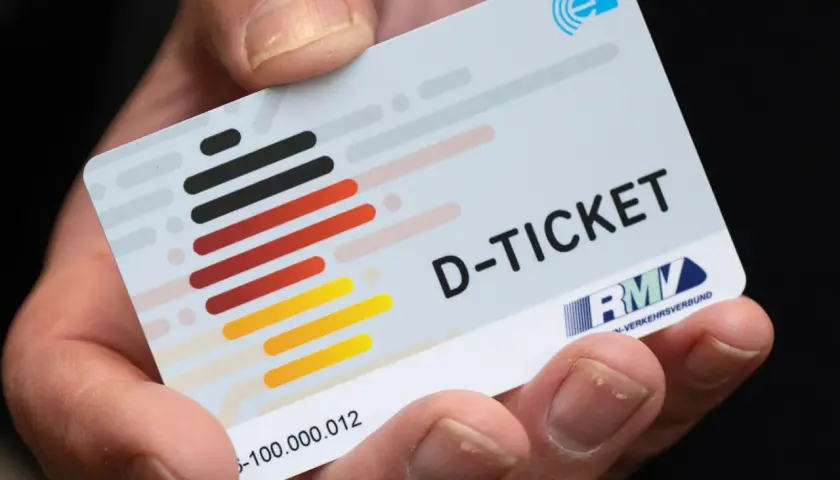 Ein Finger hält das Deutschlandticket. Mit diesem Ticket kann man bequem mit dem ICE und anderen Zügen durch Deutschland reisen.