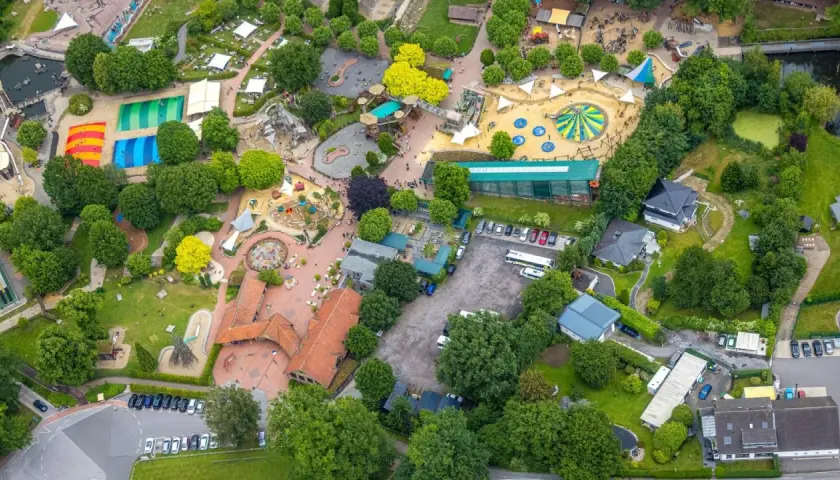 Luftaufnahme eines Freizeitparks mit bunten Spielplätzen, Trampolinen und viel Grün. Hier toben die nrw kids ausgelassen.