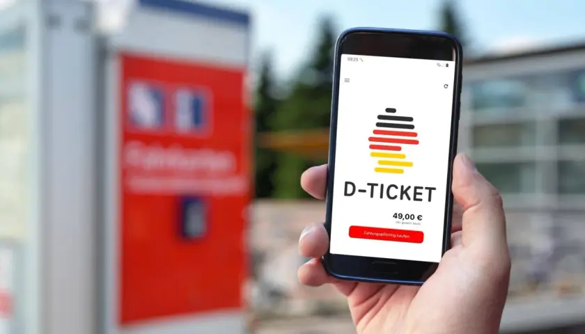 Hand hält Smartphone mit D-Ticket App. Preis 49,00 € wird angezeigt. Einfach das Deutschlandticket aktualisieren und losfahren.