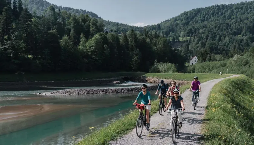 Eine Gruppe radelt entlang eines Flusses in den Bergen. Die komoot Fahrrad App hat sie sicher hierher geführt.