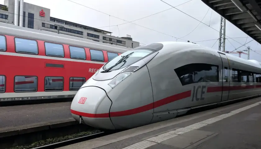 ICE-Zug und roter Regionalzug am Bahnsteig. Der ICE ist bereit für die Fahrt, wie ein ausgedrucktes Ticket zum Einsteigen.