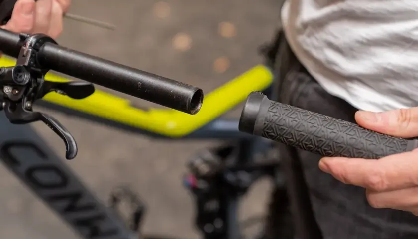 Person wechselt Lenkergriffe am Fahrrad. Ein neuer Griff wird auf den Lenker geschoben.