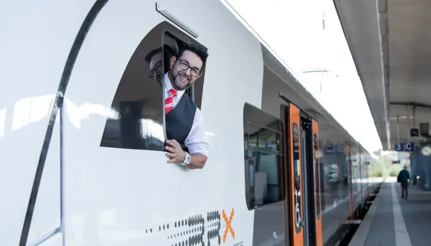 Ein freundlicher Lokführer winkt aus dem Fenster eines RRX Zuges.