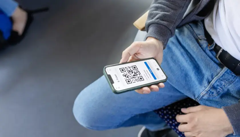Person zeigt Smartphone mit QR-Code für Deutschlandticket-Kontrolle.