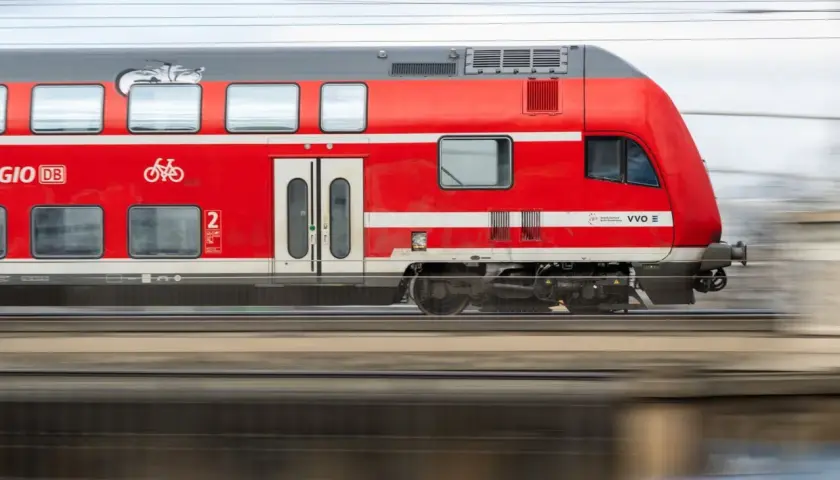 Roter Doppelstockzug der Deutschen Bahn fährt schnell. Ein Fahrradsymbol weist auf Fahrradmitnahme hin. Ideal für den Nahverkehr.