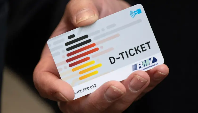 Hand hält ein D-Ticket mit Deutschlandfarben. Hoffentlich wurde das Deutschlandticket nicht doppelt gebucht!