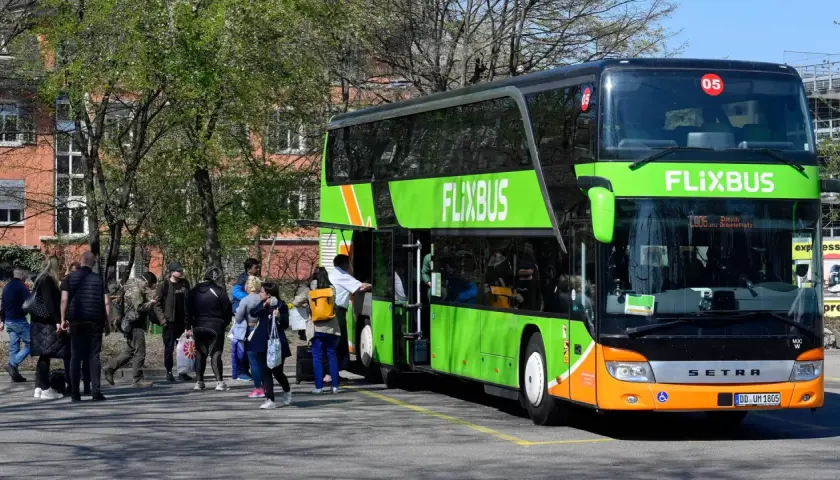 Menschen warten auf den Flixbus, der nicht kommt. Wo anrufen? Der grüne Doppeldeckerbus steht bereit, doch die Fahrgäste sind unsicher.