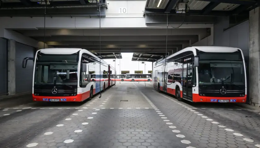 Zwei moderne Stadtbusse stehen unter einem Vordach. Man fragt sich, wie viel PS ein Bus hat, um diese Giganten zu bewegen.