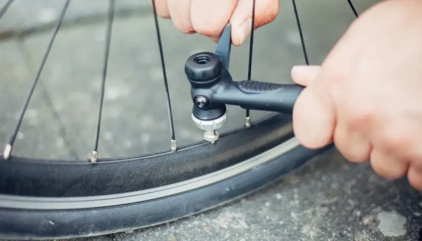 Hände pumpen mit einer Handpumpe Luft in ein Fahrradventil.