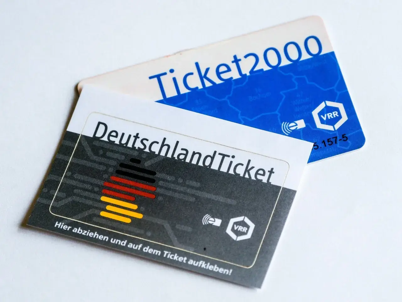 Zwei Fahrkarten liegen übereinander: das Deutschlandticket und ein Ticket2000. Sie zeigen, wie lange man mit einem Einzelticket fahren kann.