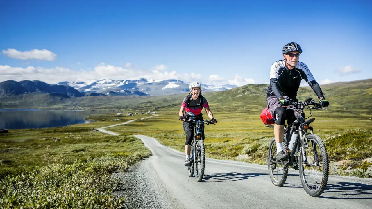 Zwei Radfahrer genießen eine atemberaubende Radtour in Schweden. Berge und ein See bilden die Kulisse für ihr Abenteuer.