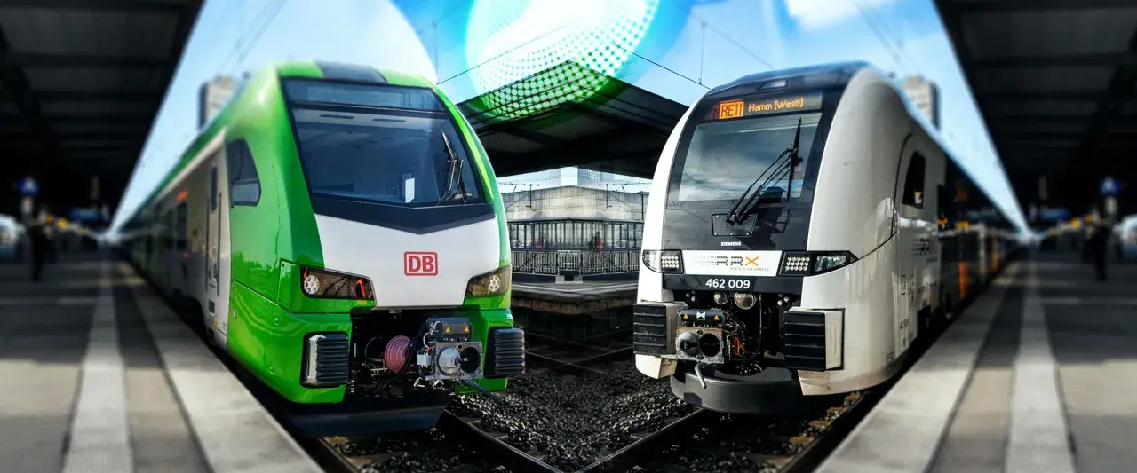 Zwei moderne Züge, ein grüner DB und ein weißer RRX, stehen nebeneinander am Bahnsteig.