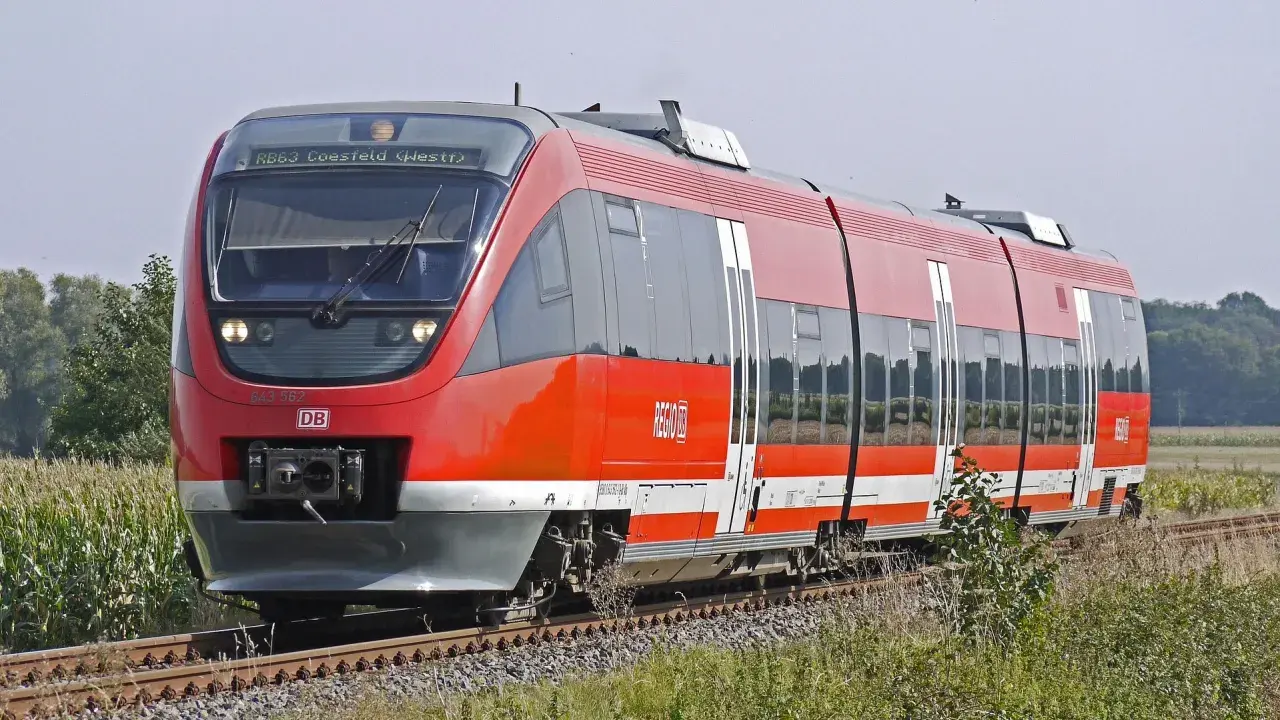 Roter Regionalexpress der DB fährt durch Kornfelder. Mit dem Deutschlandticket ist diese Fahrt ein Vergnügen.