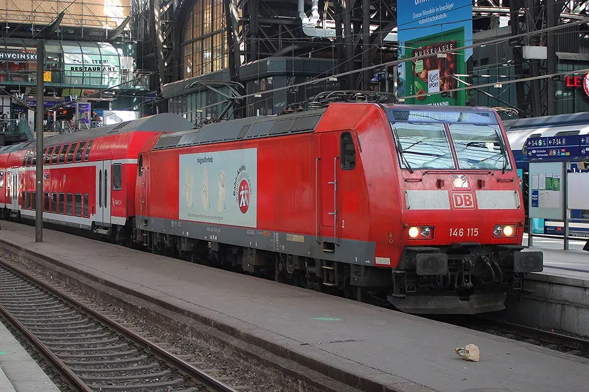 Rote Lokomotive der Baureihe 146 mit Doppelstockwagen im Bahnhof.