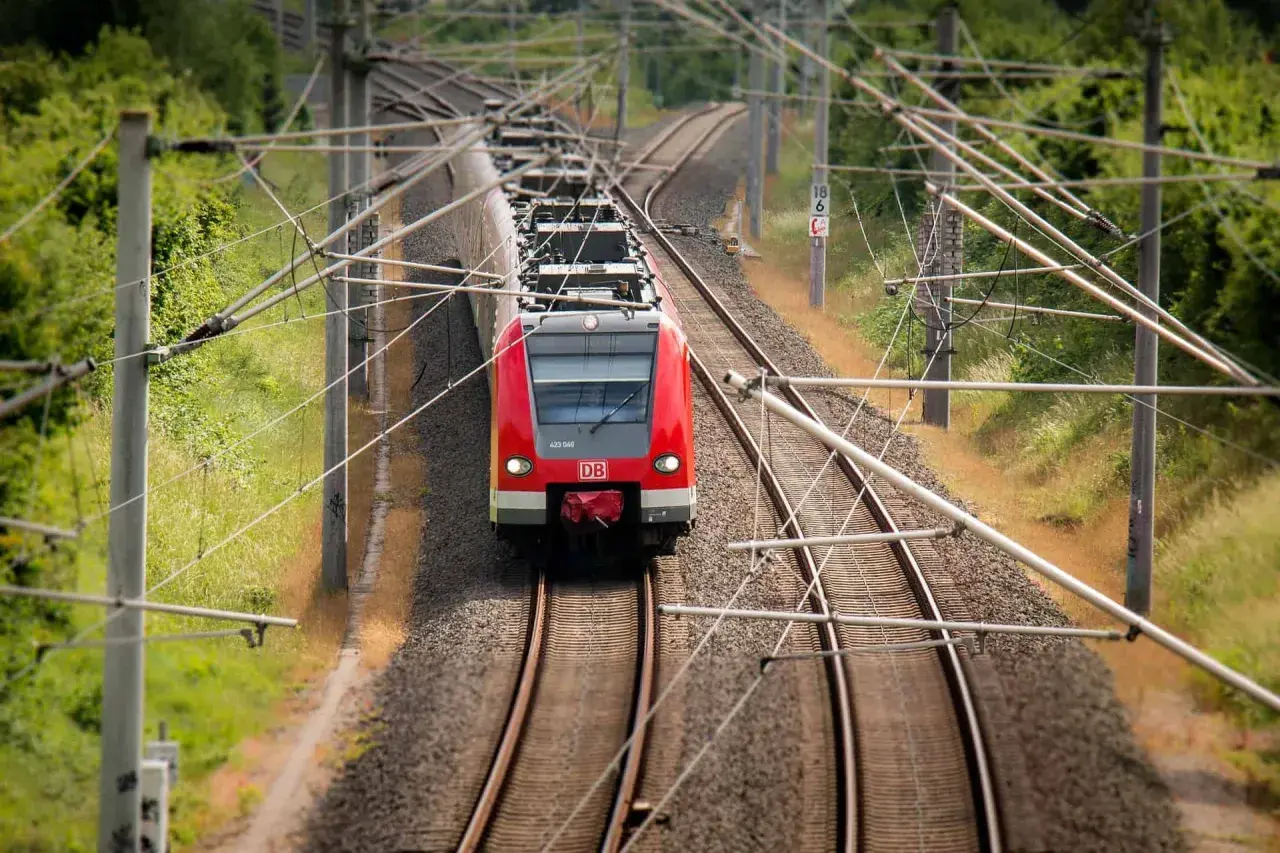 Rote DB-Bahn fährt auf Gleisen. Hier kann man alte Fahrscheine umtauschen, wenn man die Reise neu plant.