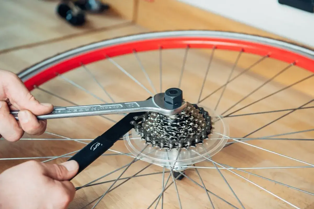Werkzeug löst die Kassette am Fahrrad. Hände halten Werkzeug und Kettenpeitsche, um die Kassette zu wechseln.