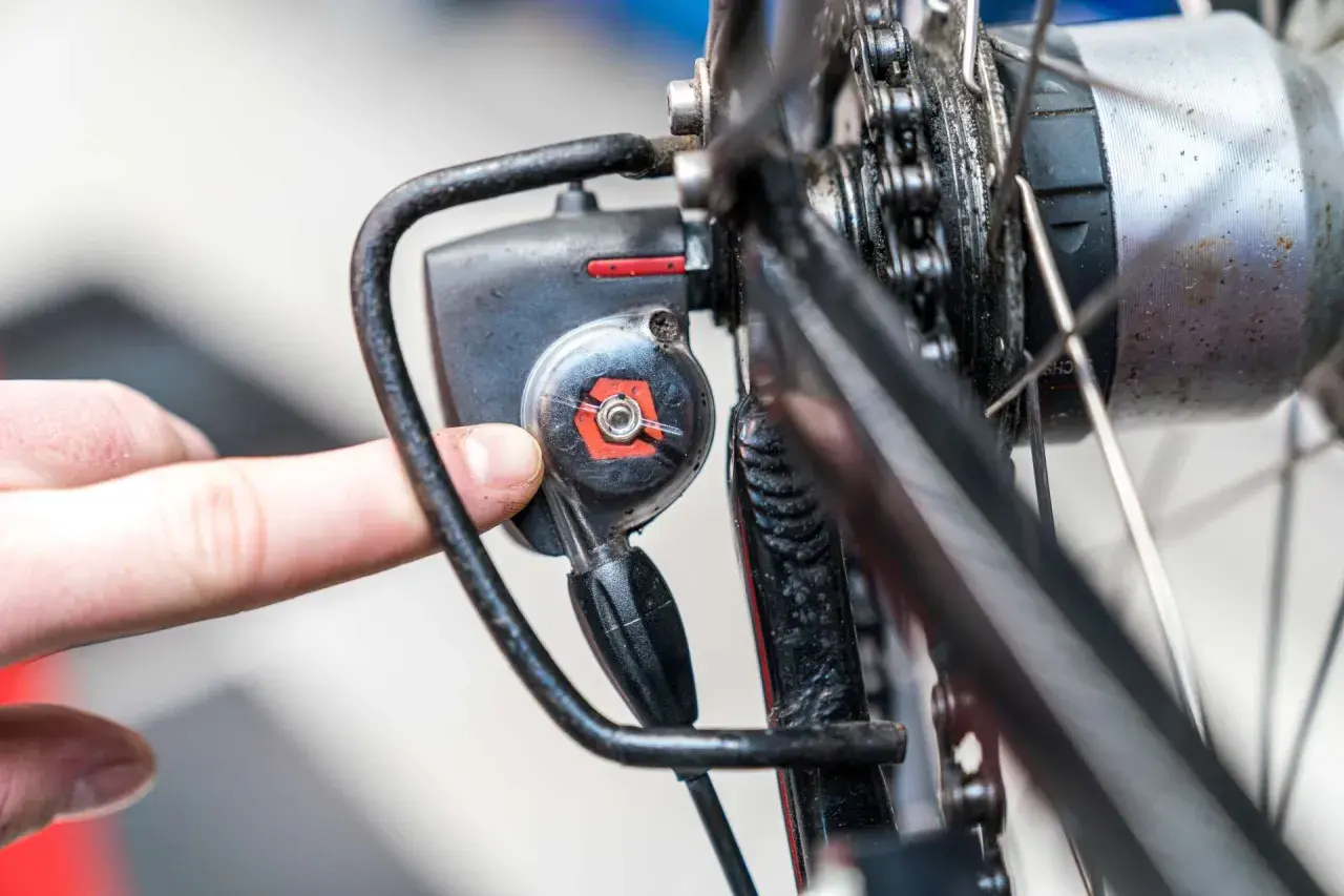 Finger dreht an Einstellschraube, um die Nabenschaltung am Fahrrad zu justieren.
