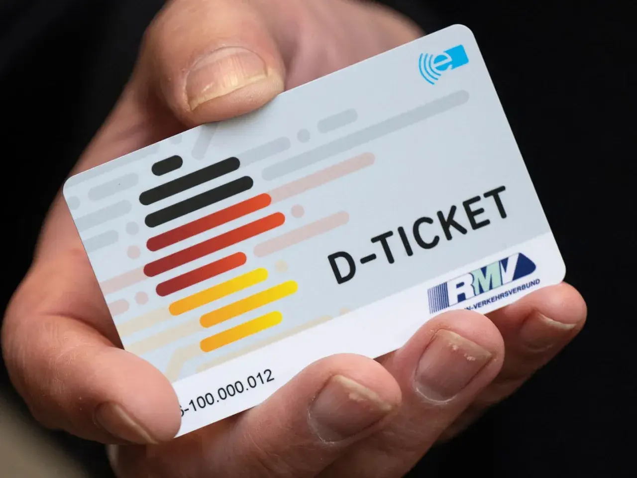 Ein Finger hält das Deutschlandticket. Mit diesem Ticket kann man bequem mit dem ICE und anderen Zügen durch Deutschland reisen.