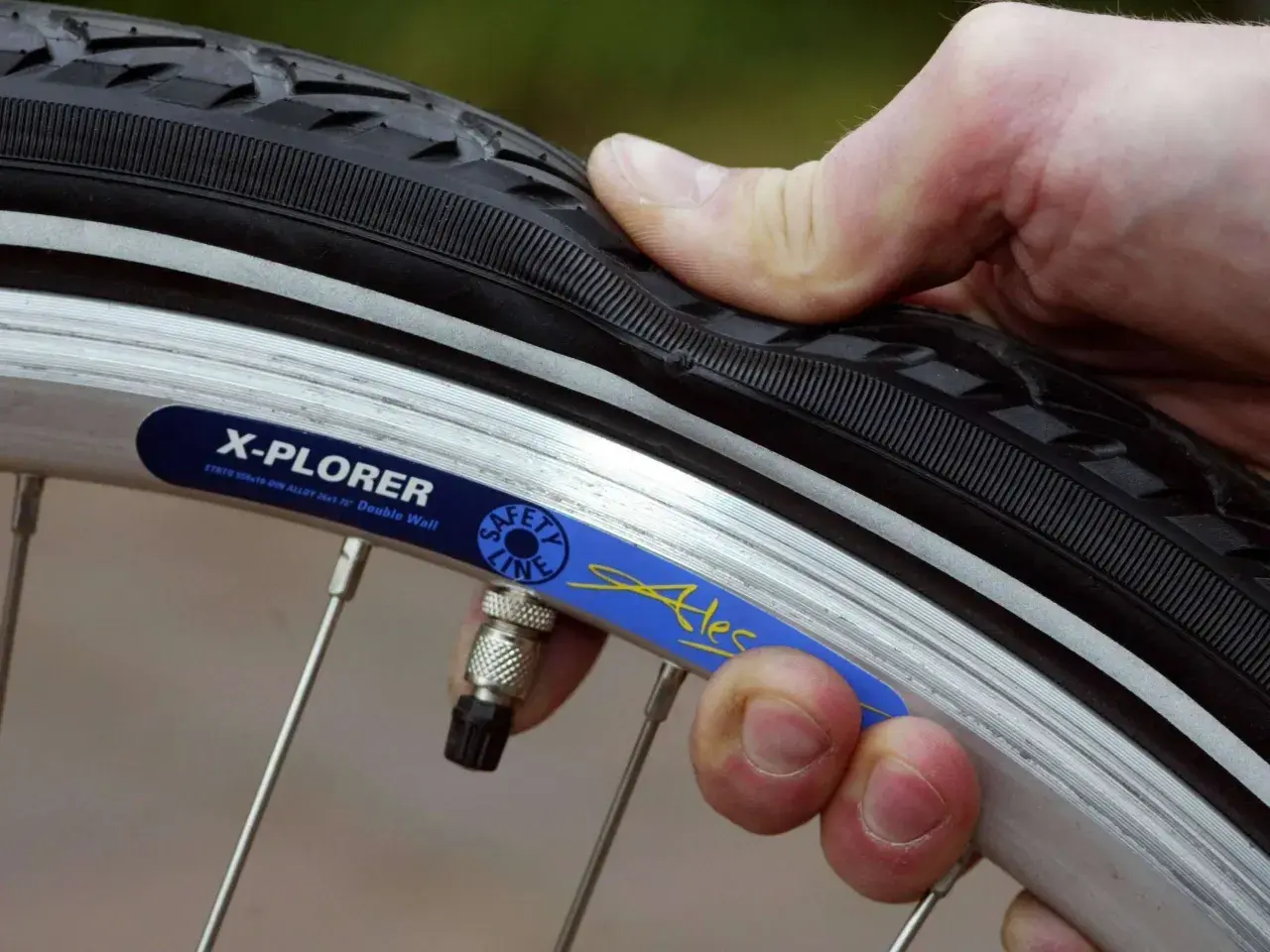 Daumen prüft den Fahrradreifen. Wie viel bar braucht der Reifen? Die Felge zeigt "X-PLORER".