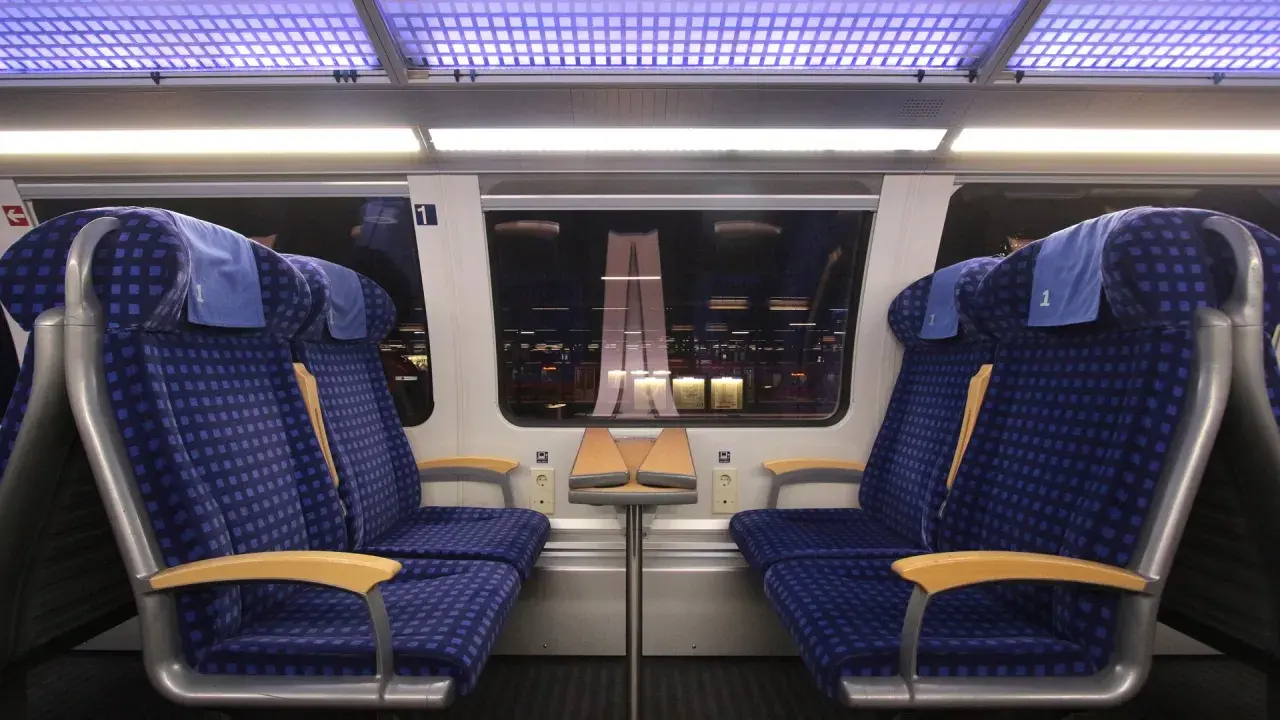 Zwei blaue Sitze der 1. Klasse im Zug, bereit für die Fahrt. Mein re1 ticket ist gelöst.