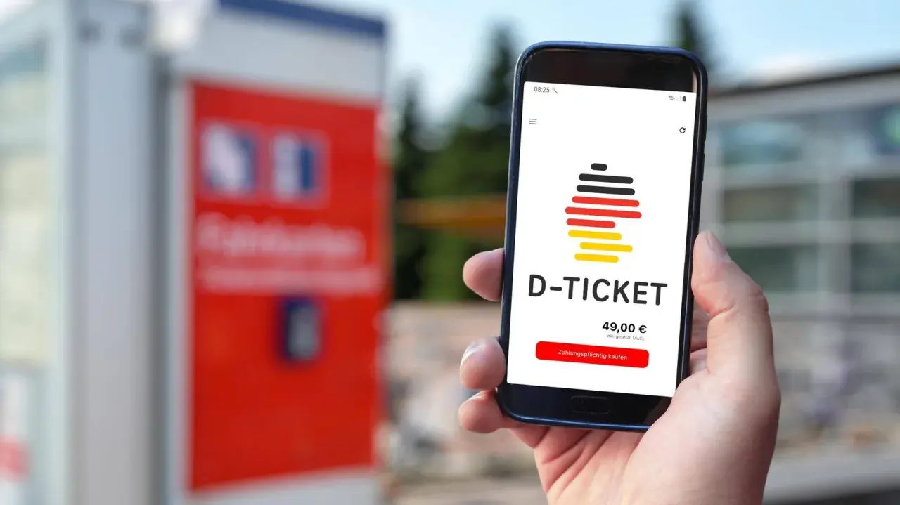 Hand hält Smartphone mit D-Ticket App. Preis 49,00 € wird angezeigt. Einfach das Deutschlandticket aktualisieren und losfahren.