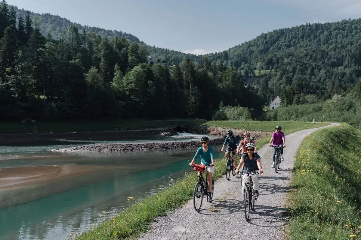 Eine Gruppe radelt entlang eines Flusses in den Bergen. Die komoot Fahrrad App hat sie sicher hierher geführt.
