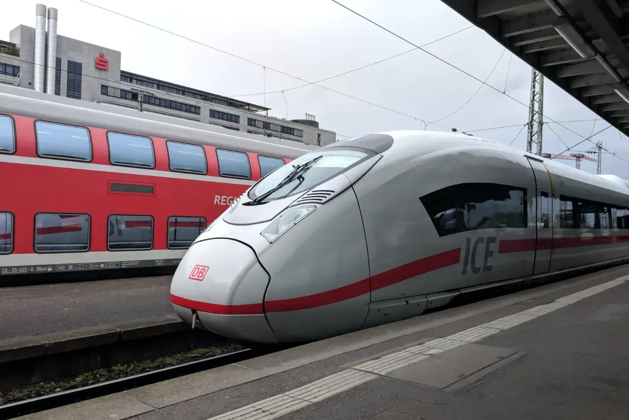 ICE-Zug und roter Regionalzug am Bahnsteig. Der ICE ist bereit für die Fahrt, wie ein ausgedrucktes Ticket zum Einsteigen.