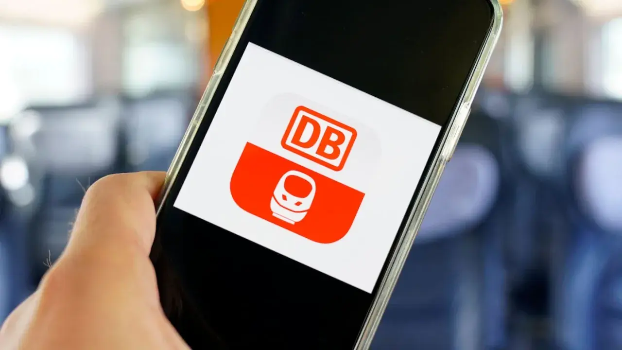 Hand hält Smartphone mit DB-App. Hier kann man unkompliziert ein DB Ticket stornieren.