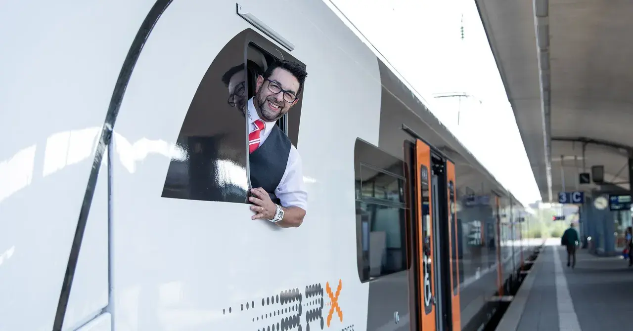 Ein freundlicher Lokführer winkt aus dem Fenster eines RRX Zuges.