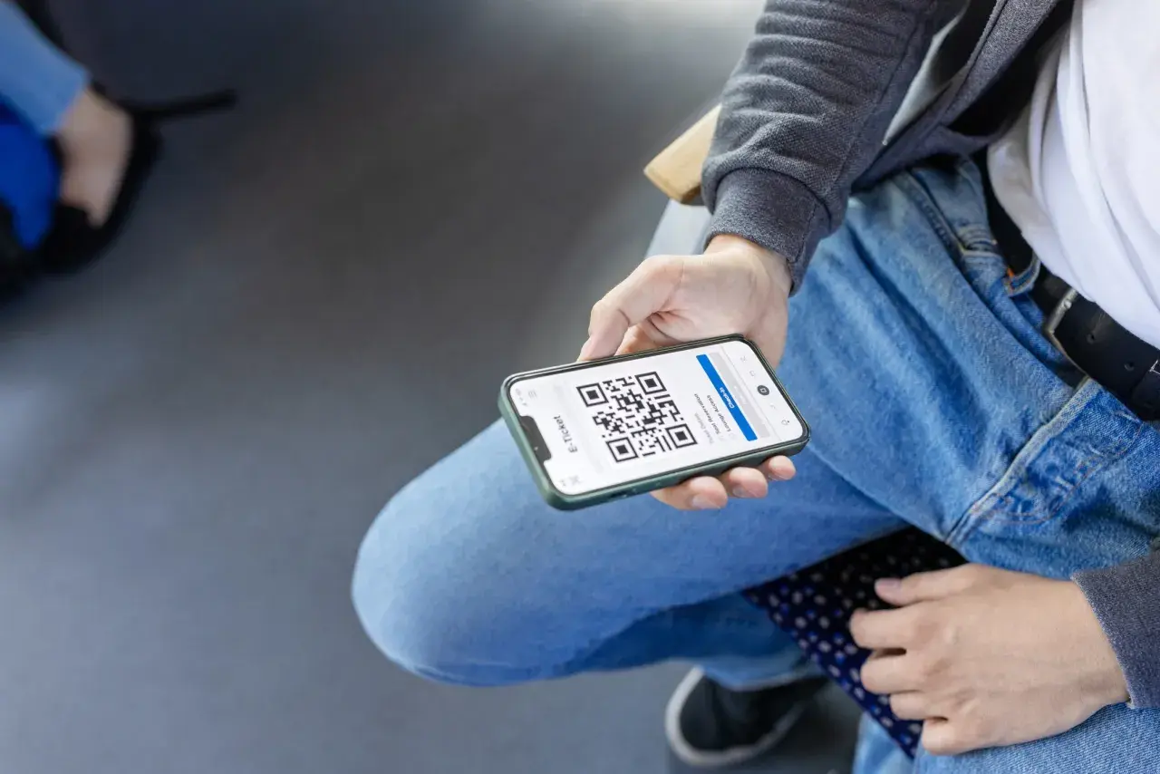 Person zeigt Smartphone mit QR-Code für Deutschlandticket-Kontrolle.