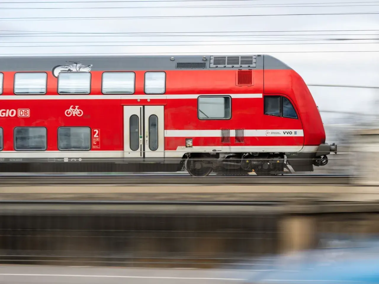 Roter Doppelstockzug der Deutschen Bahn fährt schnell. Ein Fahrradsymbol weist auf Fahrradmitnahme hin. Ideal für den Nahverkehr.