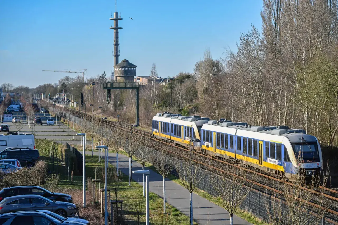 Zwei blaue und gelbe Züge der RB37 NRW fahren auf den Gleisen. Im Hintergrund ein Wasserturm und ein Sendemast.
