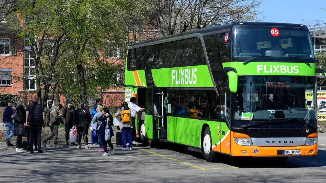 Menschen warten auf den Flixbus, der nicht kommt. Wo anrufen? Der grüne Doppeldeckerbus steht bereit, doch die Fahrgäste sind unsicher.