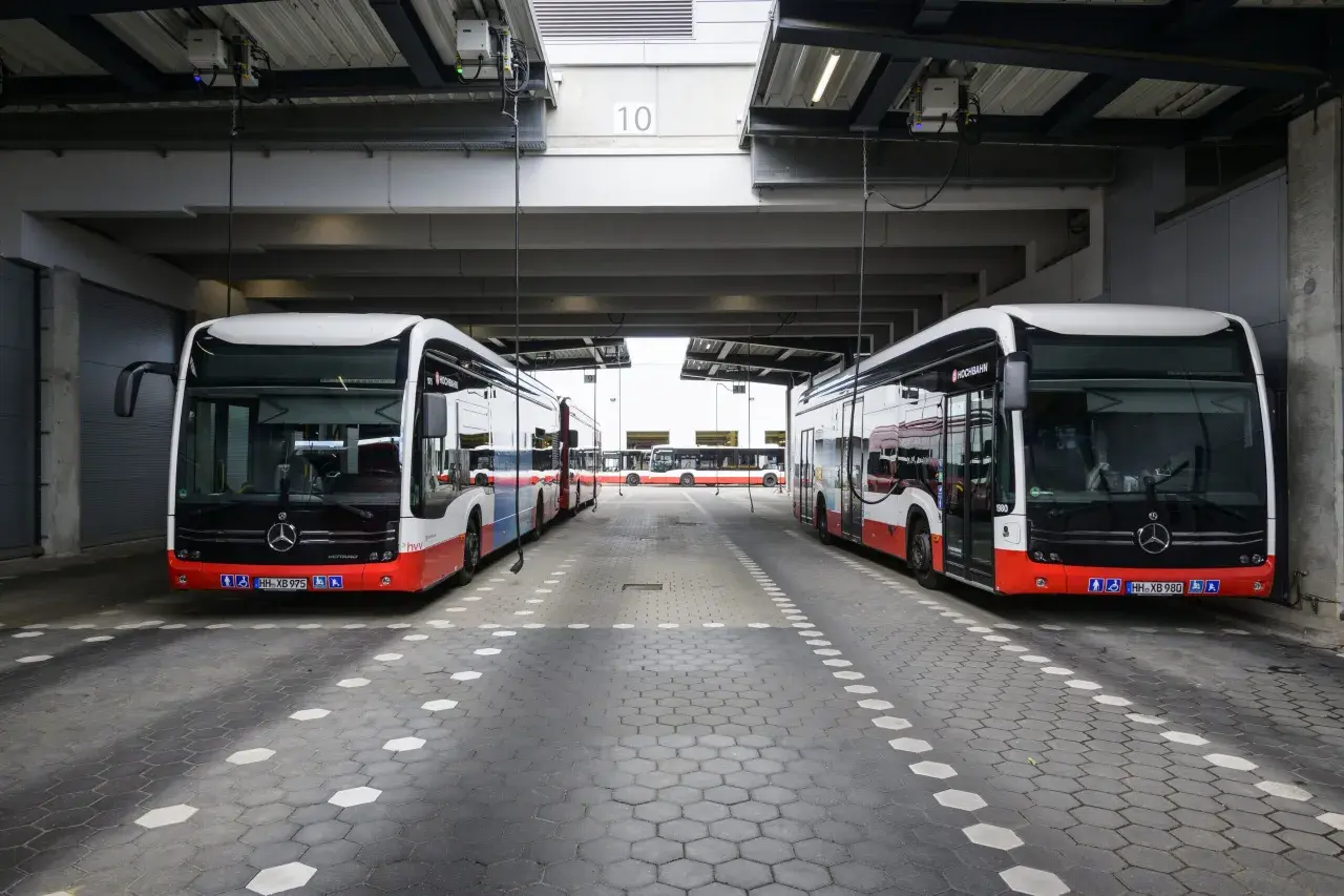 Zwei moderne Stadtbusse stehen unter einem Vordach. Man fragt sich, wie viel PS ein Bus hat, um diese Giganten zu bewegen.