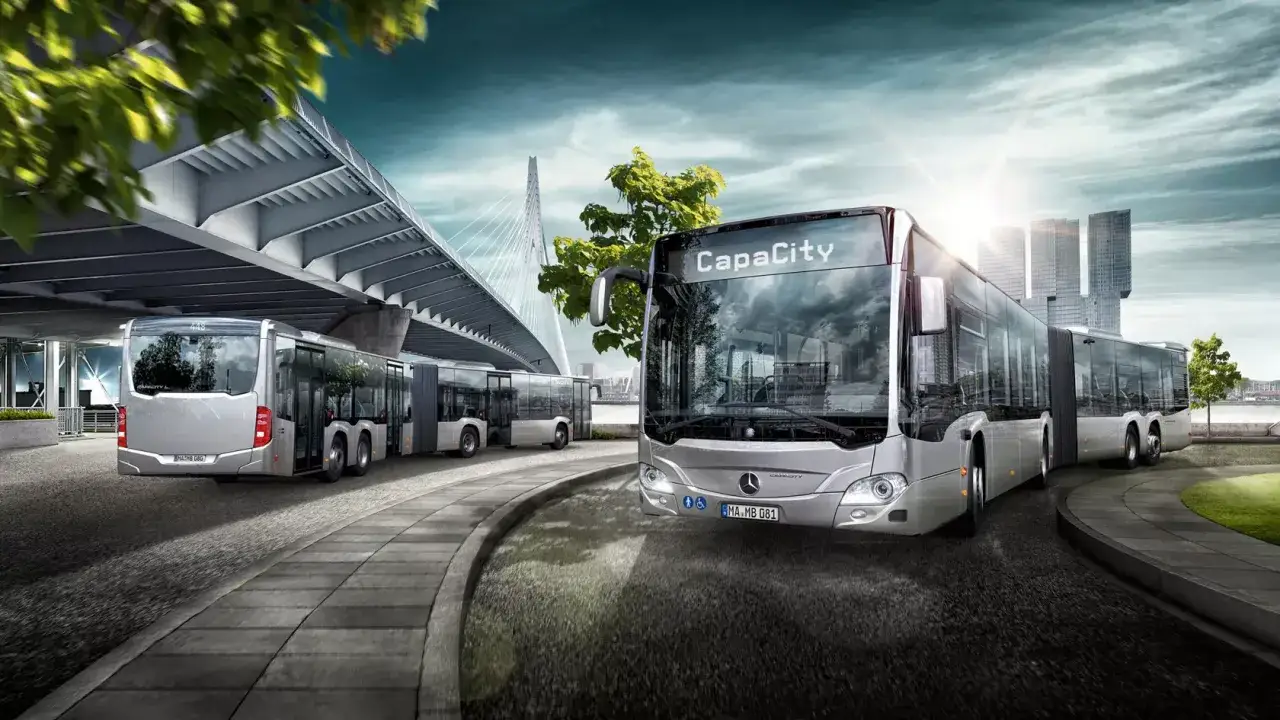 Mehrere moderne Gelenkbusse stehen an einer Haltestelle unter einer Br&uuml;cke. Die Frage 