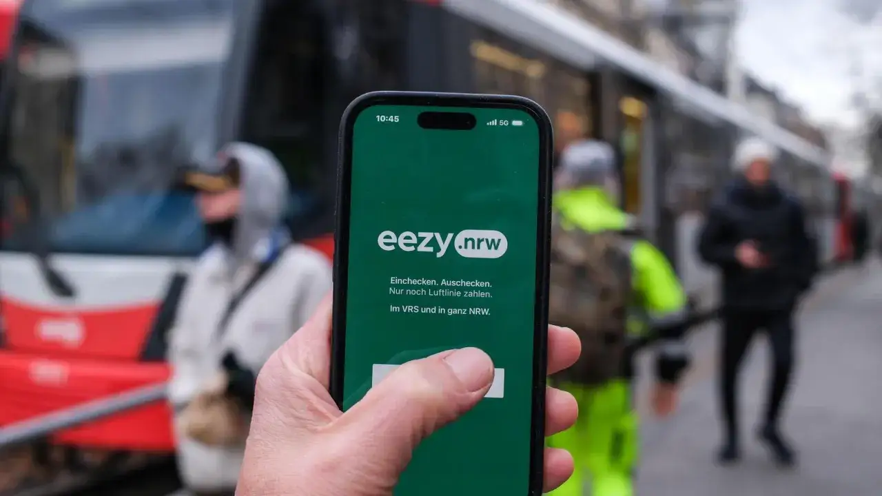 Hand h&auml;lt Smartphone mit der eezy.nrw App. Einchecken, auschecken, nur Luftlinie zahlen &ndash; so einfach ist mobiles Reisen in Westfalen.