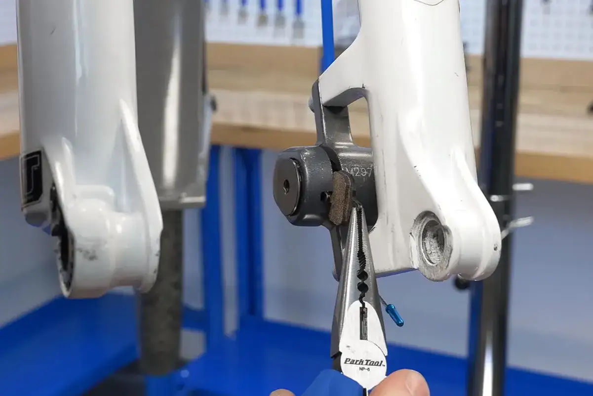 Werkzeug greift Bremsbelag, um ihn am Fahrrad zu wechseln.