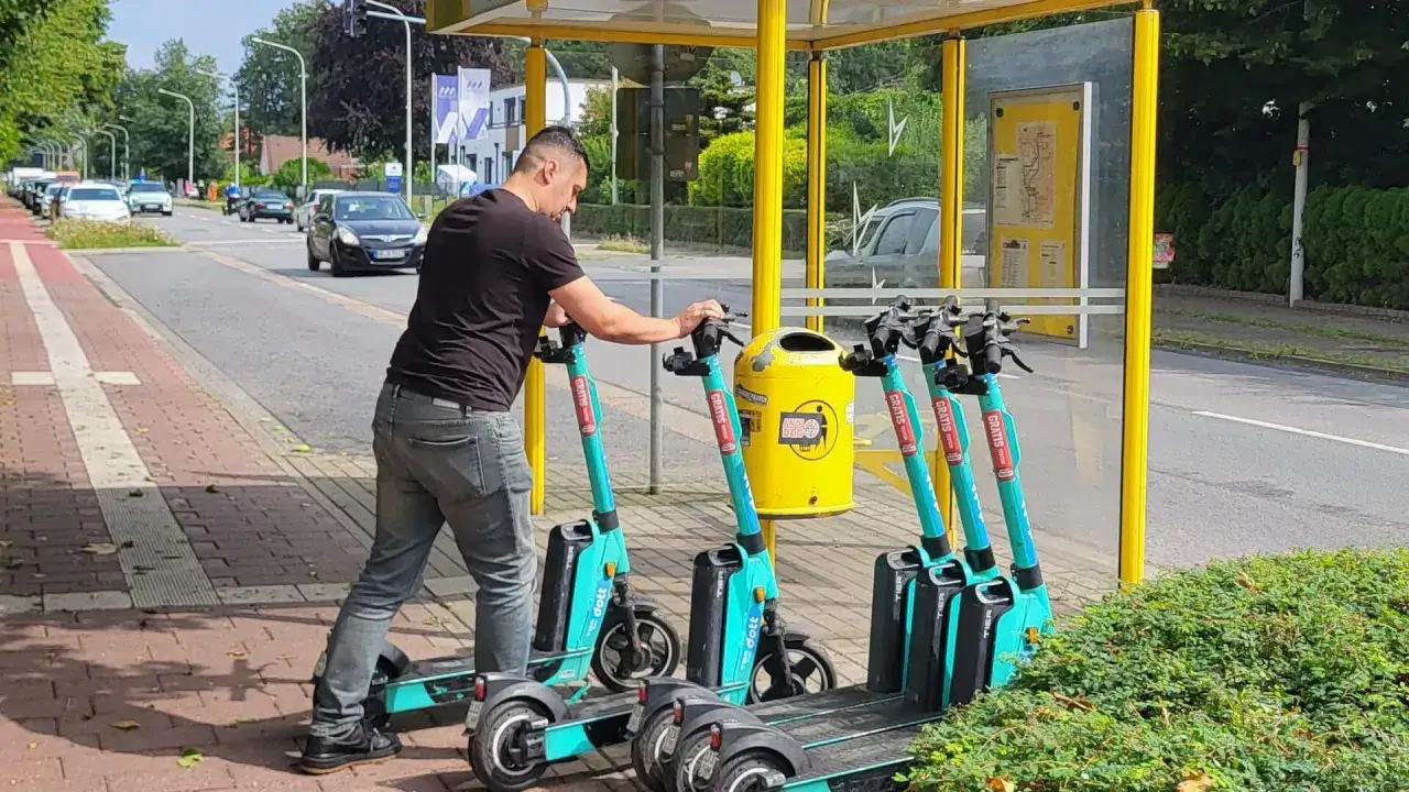 Mann schiebt E-Scooter. Die Frage 