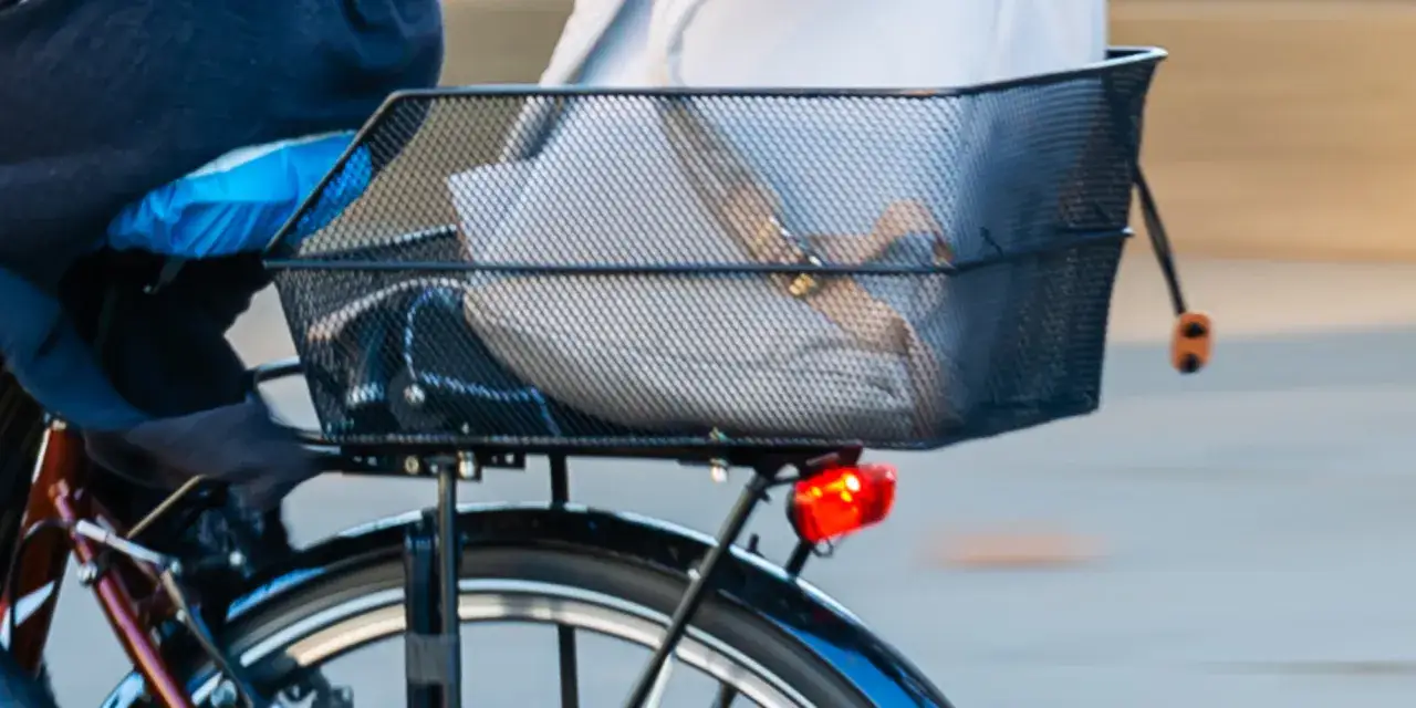 Anleitung: Fahrradkorb hinten befestigen. Ein schwarzer Drahtkorb mit Gep&auml;ck ist auf einem Fahrrad montiert.