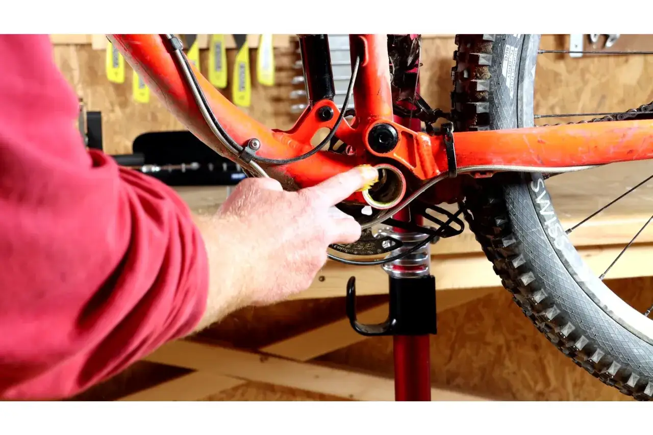 Hand schmiert Lager am roten Fahrradrahmen, um knacken der Fahrrad Pedale zu verhindern.
