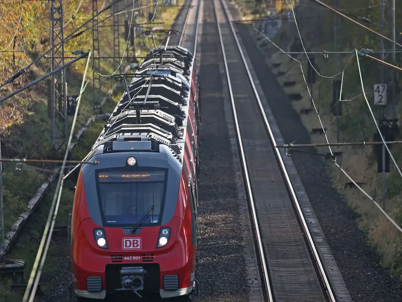 Roter ICE der re8 nrw f&auml;hrt auf zweigleisiger Strecke durch herbstliche Landschaft.