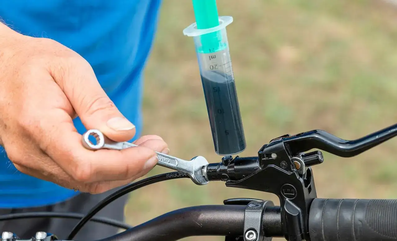 Person stellt hydraulische bremse fahrrad ein, f&uuml;llt Bremsfl&uuml;ssigkeit mit Spritze ein.