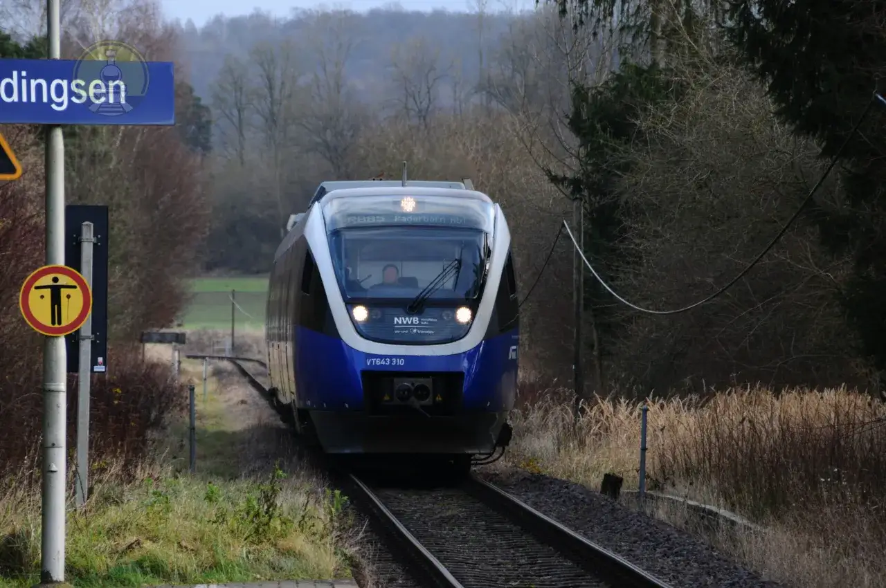Ein blauer Zug f&auml;hrt auf den Gleisen in Richtung Paderborn Hbf. Ein Schild mit 