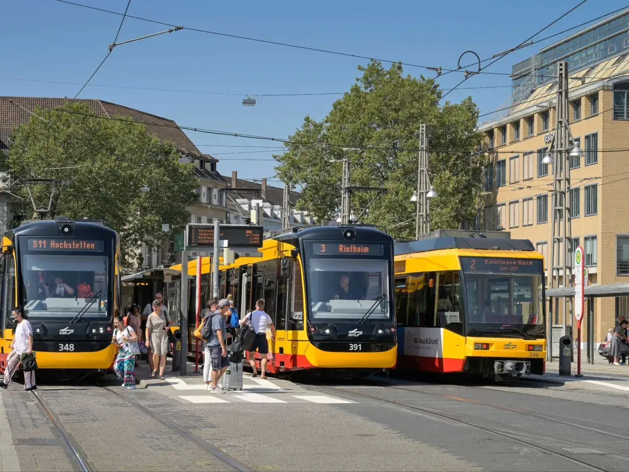 Drei Bahnen warten an einer Haltestelle. Menschen steigen ein und aus. Das ist, was gilt als Nahverkehr.